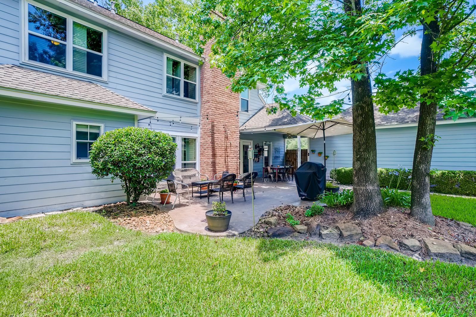 Concrete and brick patio with outdoor furniture beside a house